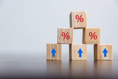 Yüzdelik sembollü yakın çekim tahta küpleri, tahta küplerde yüzde ve yukarı doğru yükselen oklar. Mali faiz ipotek oranlarında artış veya fiyat komisyonuna zam, büyüme işi, finans vergisi.
