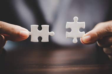 Business woman person hand holding puzzle piece idea for strategy and solution. Closeup part of two white jigsaw connect together. Concept of join cooperation success teamwork-problem corporate team
