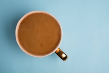 Top view to white cup with delicious coffee on blue background. Greeting card. Post card. Place for your text.