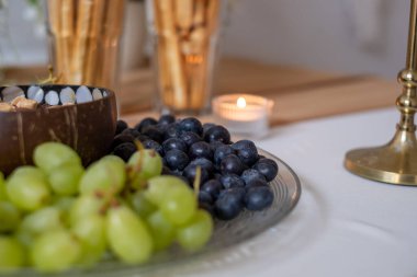 Close-up of fresh appetizing grapes and blueberries on transparent glass plate. Selective focus. Blurred background and blurred foreground.