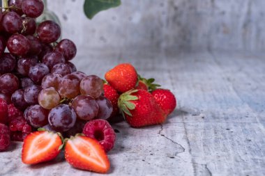 Appetizing, fresh, juicy, ripe grape, raspberry and strawberry assortment on light gray background.Excellent image for dessert banners and advertisements. Greeting card. Post card. Place for your text.