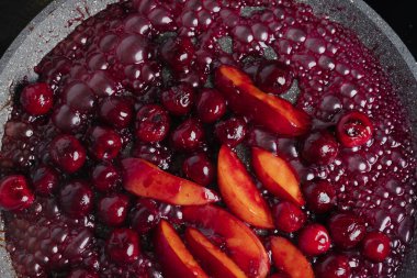 Close-up of delicious, caramelized cherries and nectarines in pan. Appetizing pan-fried fruits for dessert. Excellent image for homemade dessert banners and advertisements.
