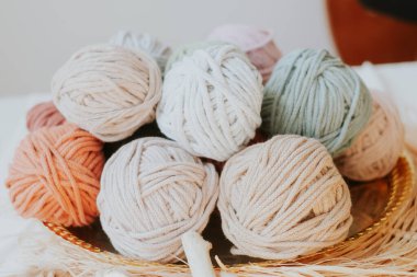 Basket with colorful, cozy cotton twine balls. Homely atmosphere. Hobby knitting. Cotton twines in warm colors. Blurred background. Excellent image for handcrafts banners and advertisements.
