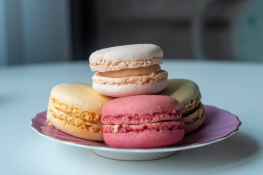 Şirin pembe tabakta renkli badem kurabiyelerinin yakın çekimi. Dumanlı bir arka plan. Güzel kavram. Tatlı afişleri ve reklamlar için mükemmel bir görüntü. Metnin için yer.