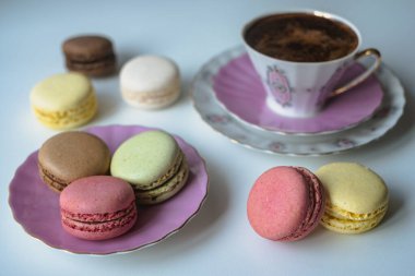 İştah açıcı badem kurabiyeleriyle porselen bardaktaki lezzetli kahvenin karışımı. Beyaz masa üzerinde bulanık çiçeklerle süslenmiş. Kuru çiçekler. Tebrik kartı.