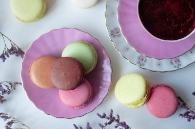 İştah açıcı badem kurabiyeleriyle porselen bardaktaki lezzetli kahvenin karışımı. Beyaz masa üzerinde bulanık çiçeklerle süslenmiş. Kuru çiçekler. Tebrik kartı.