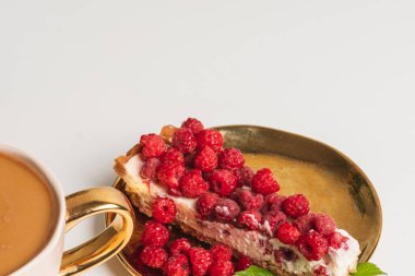 Beyaz arka planda goden tabağında taze ahududu olan lezzetli bir parça pasta. Güzel kavram. Tatlı afişleri ve reklamları için mükemmel bir görüntü. Göz kamaştırıcı yaşam tarzı, hedonik tatiller, güzel bir dinlenme, sevgi dolu bir eğlence, hayattan zevk alma, yazı yazma yeri.