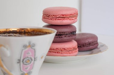 İştah açıcı pembe, sarı badem kurabiyesi ve beyaz arka planda bir fincan kahve. Beyaz masada iştah açıcı badem ve lezzetli kirazların karışımı. Tebrik kartı. Tatlı konsepti. Tatlı afişleri ve reklamlar için mükemmel bir imaj. Metin için yer.