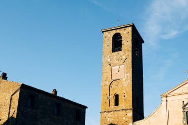 Üzerinde kare saat olan antik bir binanın eski kare kulesinin dış görüntüsü ve arka planda derin mavi gökyüzü, metin için yer, tırnak işareti için yer.