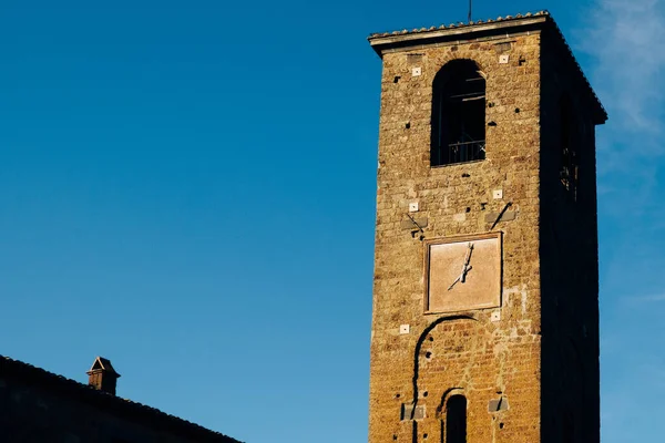 Exterior shot of old square tower of an ancient building with squared clock on it and with deep blue sky in background, place for your text, place for quotes