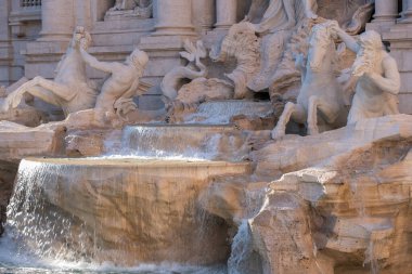 Dünyanın en ünlü simgelerinden biri olan Trevi Çeşmesi Roma 'nın parlak güneş ışığında ön planda su havzası ile çevrilidir..