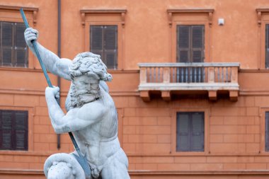 Etkileyici yenilenmiş, balkonlu, pencereli ve ön planda Neptün 'ün heybetli heykeli olan eski bir terasotta taş binaya bakın.