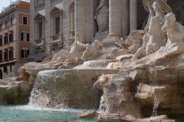 Dünyanın en ünlü simgelerinden biri olan Trevi Çeşmesi Roma 'nın parlak güneş ışığında ön planda su havzası ile çevrilidir..