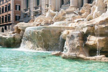 Dünyanın en ünlü simgelerinden biri olan Trevi Çeşmesi Roma 'nın parlak güneş ışığında ön planda su havzası ile çevrilidir..