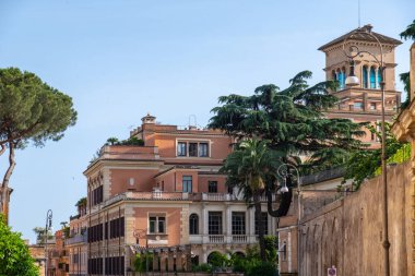 Arka planda mavi gökyüzü ve İtalyan taş çamı olan eski ve etkileyici bir terasotta taş binaya bakın.