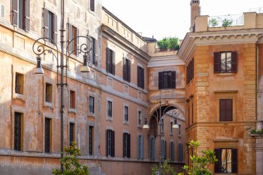 Pencere panjurlu ve kemerli eski ve etkileyici taş binaların manzarası. Ön planda klasik fener var. Eski Roma şehrinde etkileyici bir tarihi bina.