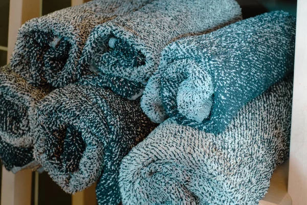 rolls of gray towels on a shelf in a spa resort, towels for relaxing treatments, a shelf with towels in the pool area, body care