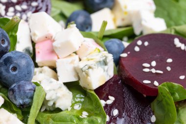 Ispanaklı, pancarlı, mavi peynirli ve susamlı lezzetli bir vejetaryen salatasıyla büyük beyaz bir tabak. Güzel servis edilmiş yemek. Sağlıklı beslenme. yiyecek arka planı.