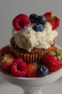 Lezzetli vejetaryen kremalı güzel kek, dekoratif beyaz bir yastıkta taze böğürtlen. Mesajın için yer aç. Güzel kavram. Tatlı afişleri ve reklamlar için mükemmel bir görüntü. Çöl arkaplanı. 