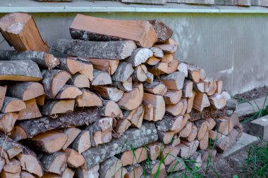 Evin duvarına karşı düzgünce düzenlenmiş odun yığını, ahır duvarına yaslanmış odun yığınları.