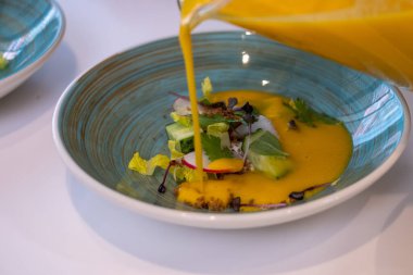 Yeşil ve sebzeli mavi tabaklar ve parlak sarı domates çorbası. Sağlıklı yemek reklamı, mutfak geçmişi..