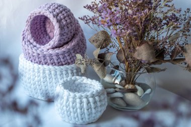 Mor şirin dekoratif el işlemeli sepetler, sürdürülebilir el işi, dekoratif mor kuru bitkiler ve beyaz arka planlı rahat ev atmosferi.