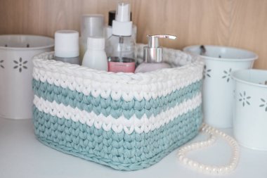Banyo aksesuarları, inci boncuklar ve depolama için beyaz metal kovalarla süslü yeşil ve beyaz çizgili dekoratif el sepetleri. Sürdürülebilir el işi, iç mekanda rahat atmosfer.