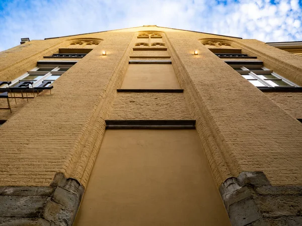 Bottom-up shot of a yellow old building in the city of Bruges.