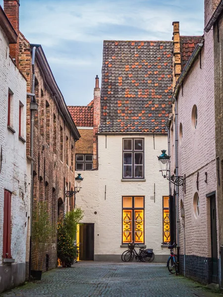 The front view of a beautiful house with its cute roof made of red and black bricks on a narrow street in Bruges, Belgium.