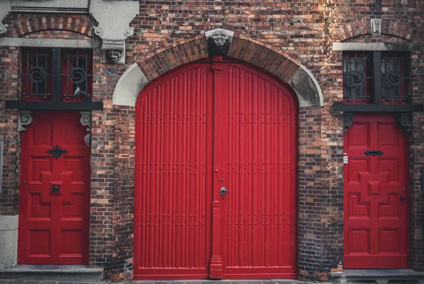 Traditional shiny wooden red entrance doors of a building in Bruges, Belgium.
