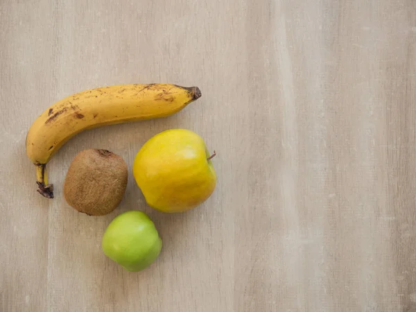 Healthy and ripe fruits on a wooden table: banana, apple, kiwi