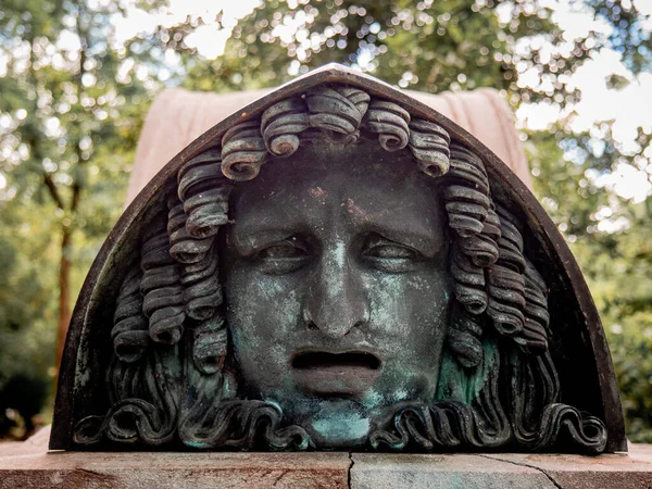 A small head sculpture in the famous Pere Lachaise cemetery in Paris, France. The cemetery is a tourist destination since many famous people sleep there.