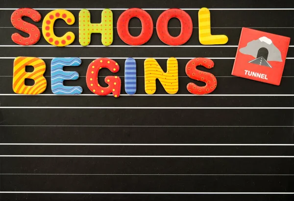 Back to school concept with colorful magnetic letters on a chalkboard as a black background. There is a free text field.