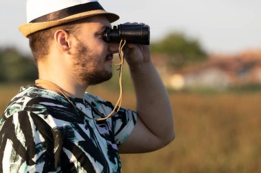 The young birdwacher with binocular obseving bird migration on the field