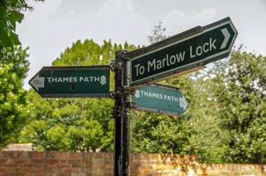 Marlow, UK - July 19, 2021: Fingerpost sign showing the direction of the Thames Path footpath next to Marlow Lock in Buckinghamshire on a sunny summer afternoon.   clipart