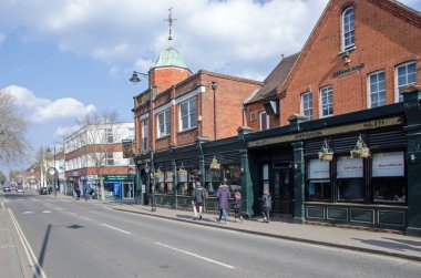 Fleet, UK - March 20, 2022: Shoppers enjoying the spring sunshine on a sunny afternoon in the high street in the Hampshire town of Fleet.  
