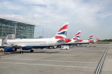 Londra, İngiltere - 19 Nisan 2022: Güneşli bir bahar sabahı Heathrow Havaalanı Terminali 'nin bir parçası olan A Kapısı' ndaki dört British Airways uçağı.