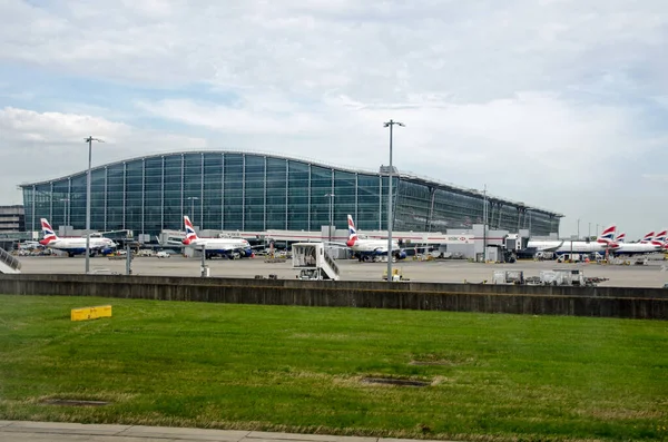 Londra, İngiltere - 19 Nisan 2022: Güneşli bir bahar sabahı, Londra 'nın Heathrow Havalimanı' ndaki 5 numaralı ana terminaldeki İngiliz Hava Yolları uçaklarıyla dolu stantlar.  