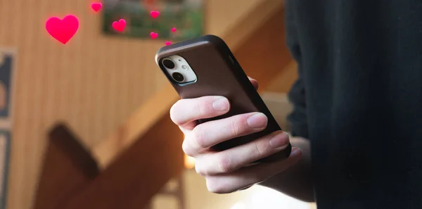 Young man giving likes (likes in the form of hearts) on his mobile phone on a social network
