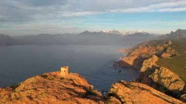 Aerial view of the Capo Rosso Tower in Corsica. Drone view of the Turghiu tower at sunset in France. Mediterranean Sea coastline