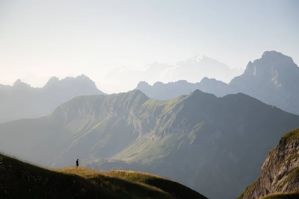 Man silhouette staring at the vastness of the mountains surrounding him. Mont Blanc mountains at sunrise in French Alps from the Lake of Peyre.