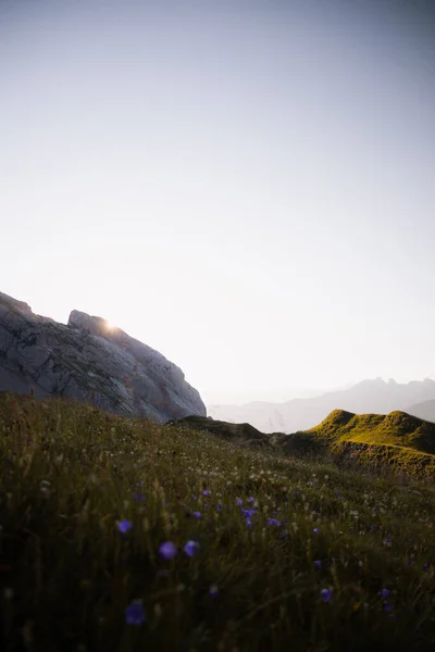 Vertical photo of the rising sun behind a mountain in French Alps. Sunrise at the lake of Peyre in Alps