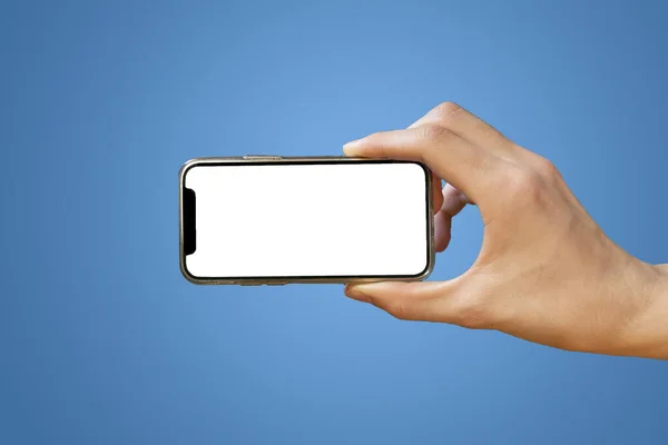 Mobile phone with empty white screen in hand on bright blue background