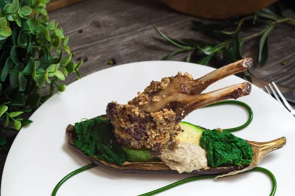 Rack of lamb in nut batter with baked vegetables. Spinach paste and baked eggplant. Molecular food.