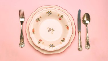 top view of plate with cutlery and knife on pink background