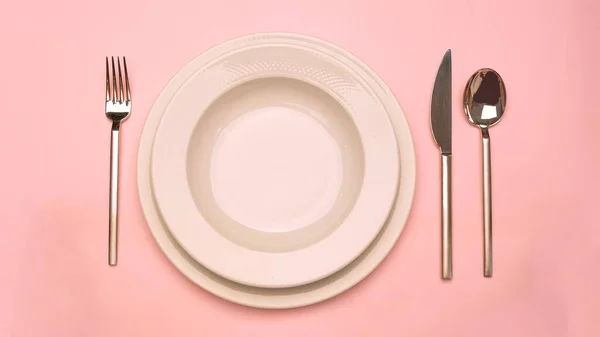 empty plate and fork on pink background