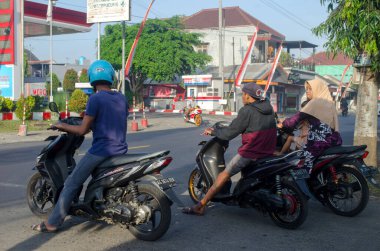 Malang, Endonezya - 4 Eylül 2022: Sabahleyin Malang, Endonezya 'da seyahat etmek için karşıdan karşıya geçen üç motosikletçi