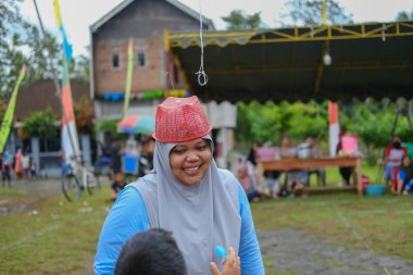 Blitar, Endonezya - 11 Eylül 2022: Blitar 'da düzenlenen Endonezya Bağımsızlık Günü yarışmasında çocuğu tarafından cesaretlendirilen peçeli bir anne