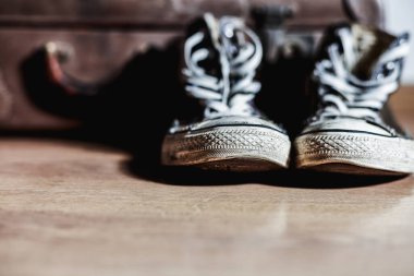 Old sneakers with vintage suitcase in background