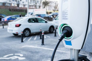 Electric car charger close up with cars in background in the parking